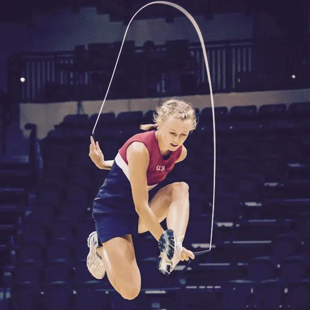 Course instructor Megan Friesth mid-air during a jump rope trick in an arena